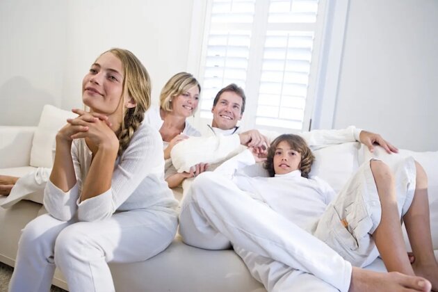 Family sitting together on white sofa watching television Family sitting together on white sofa watching television
