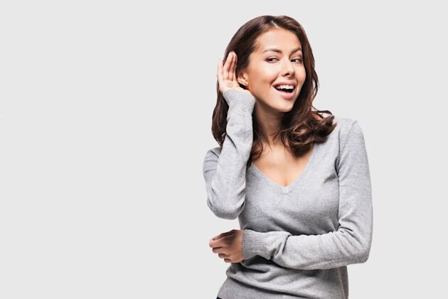 Beautiful woman puts a hand to the ear to hear better. Young girl listening something over white background Beautiful woman puts a hand to the ear to hear better. Young girl listening something over white background